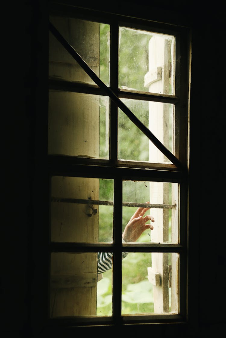 Crop Person Touching Window Of Old House