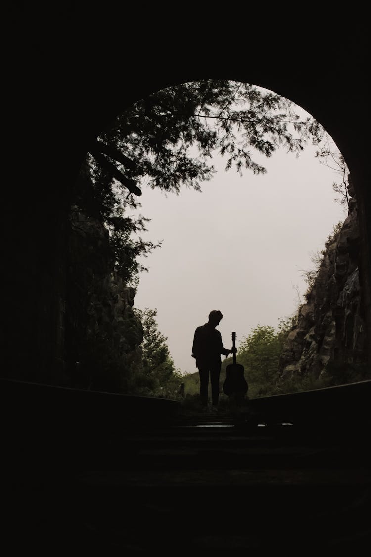 Silhouette Of Man In Tunnel Holding Guitar 