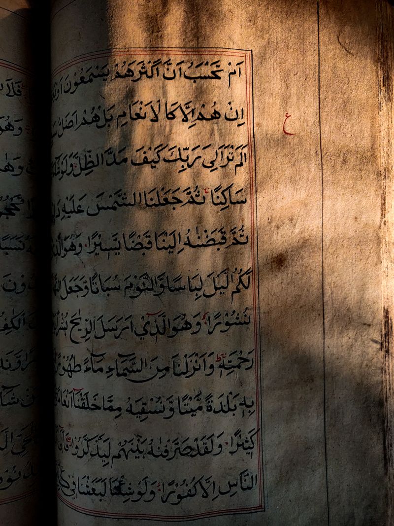 Close-up of an antique Islamic manuscript with Arabic script, highlighting the texture and aged paper.