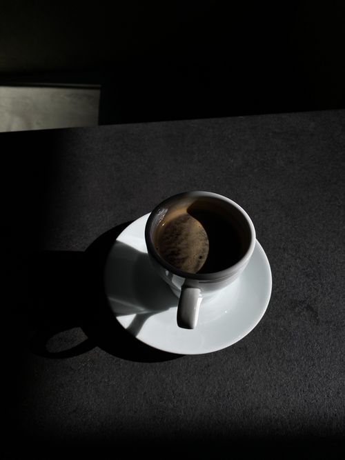 Free A minimalist photo of a coffee cup with dramatic shadows on a dark surface, perfect for design projects. Stock Photo
