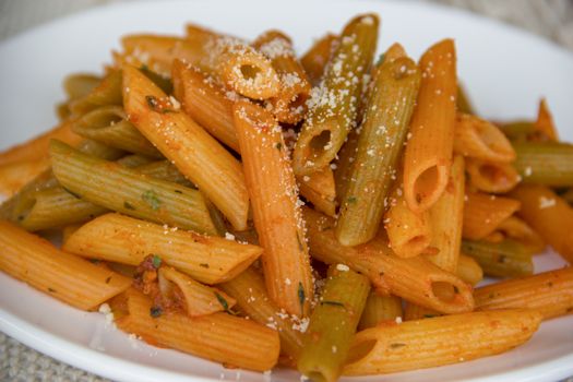 Vibrant close-up of mixed penne pasta with savory tomato and herb sauce.