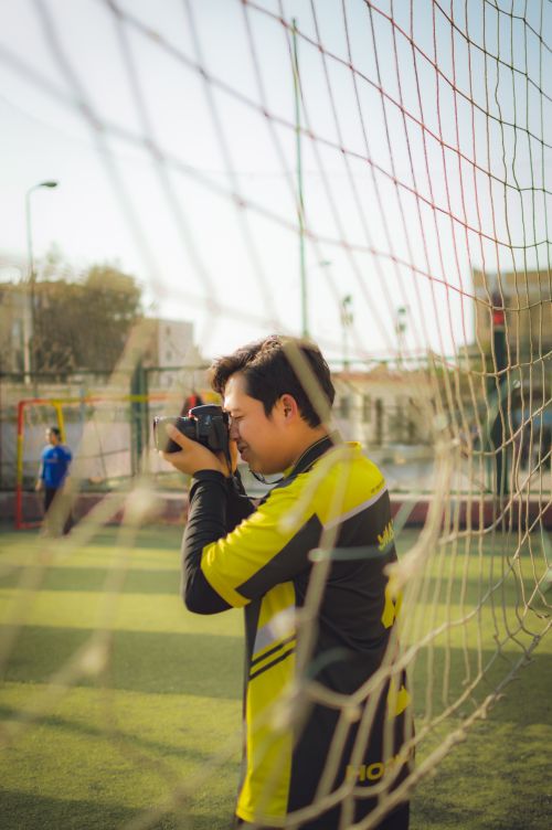 Free A photographer captures moments on a soccer field during a sunny day. Stock Photo