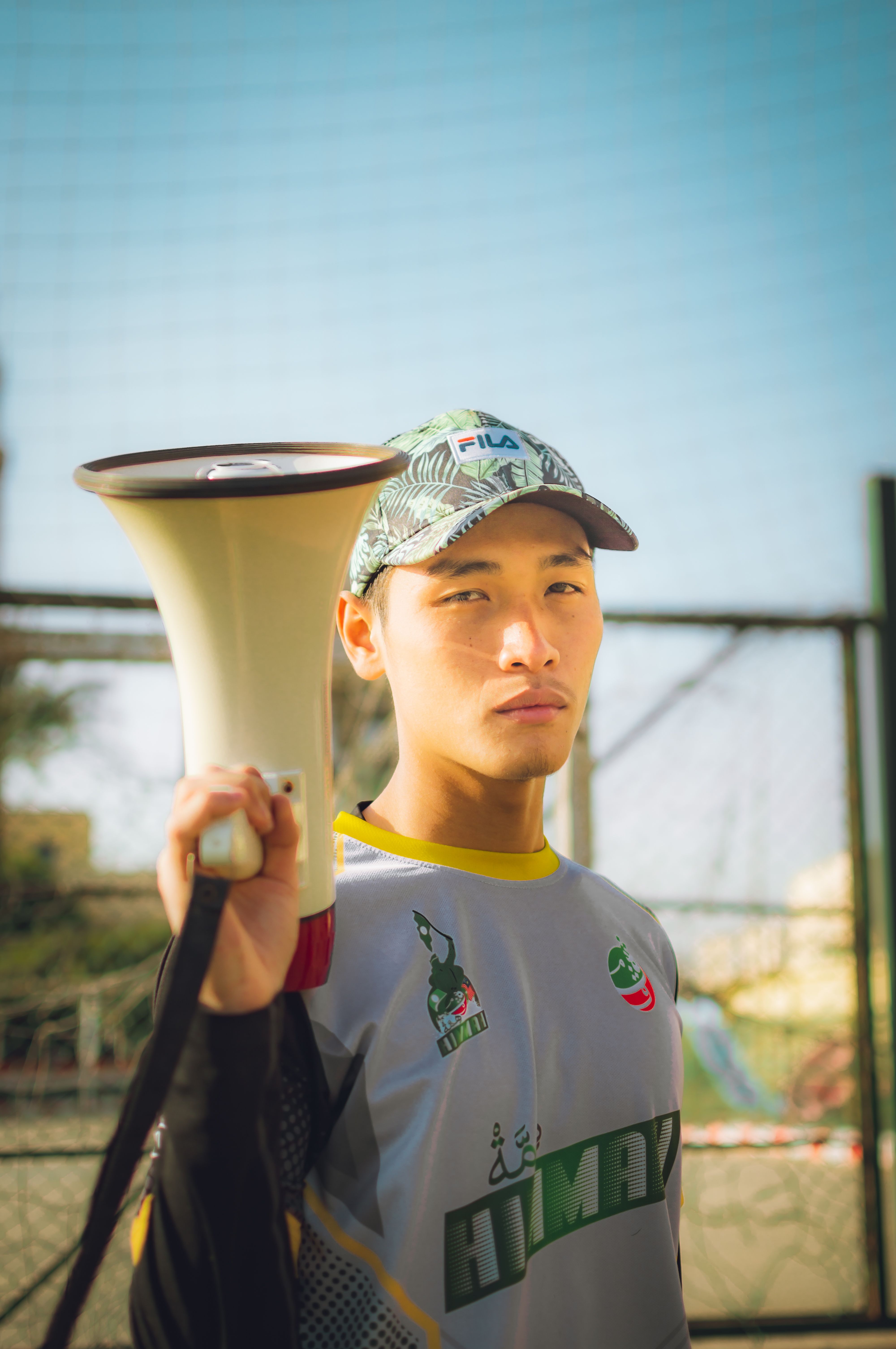 Young man holding megaphone in an outdoor setting, looking confident.