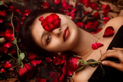 Woman Lying on Petals of Red Roses 