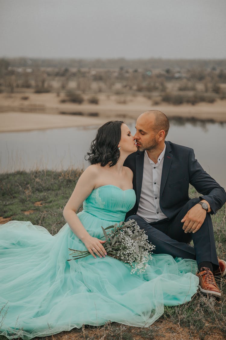 Newlywed Couple Kissing On River Coast On Wedding Day