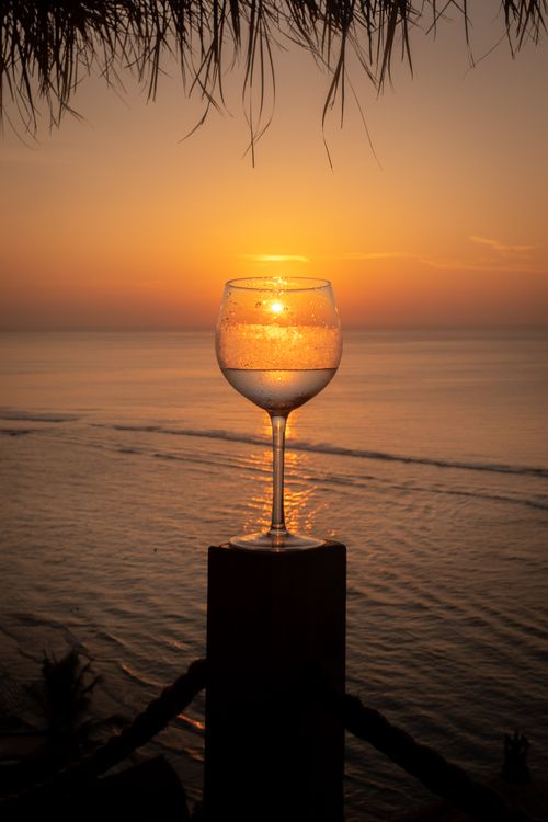 Free A wineglass silhouette against a stunning Bali sunset over the ocean, capturing tropical serenity. Stock Photo
