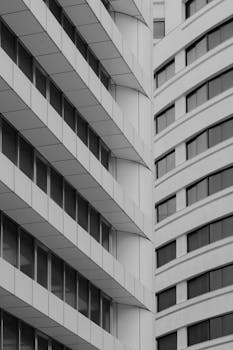 A black and white photo capturing the geometric lines of modern buildings with glass windows.