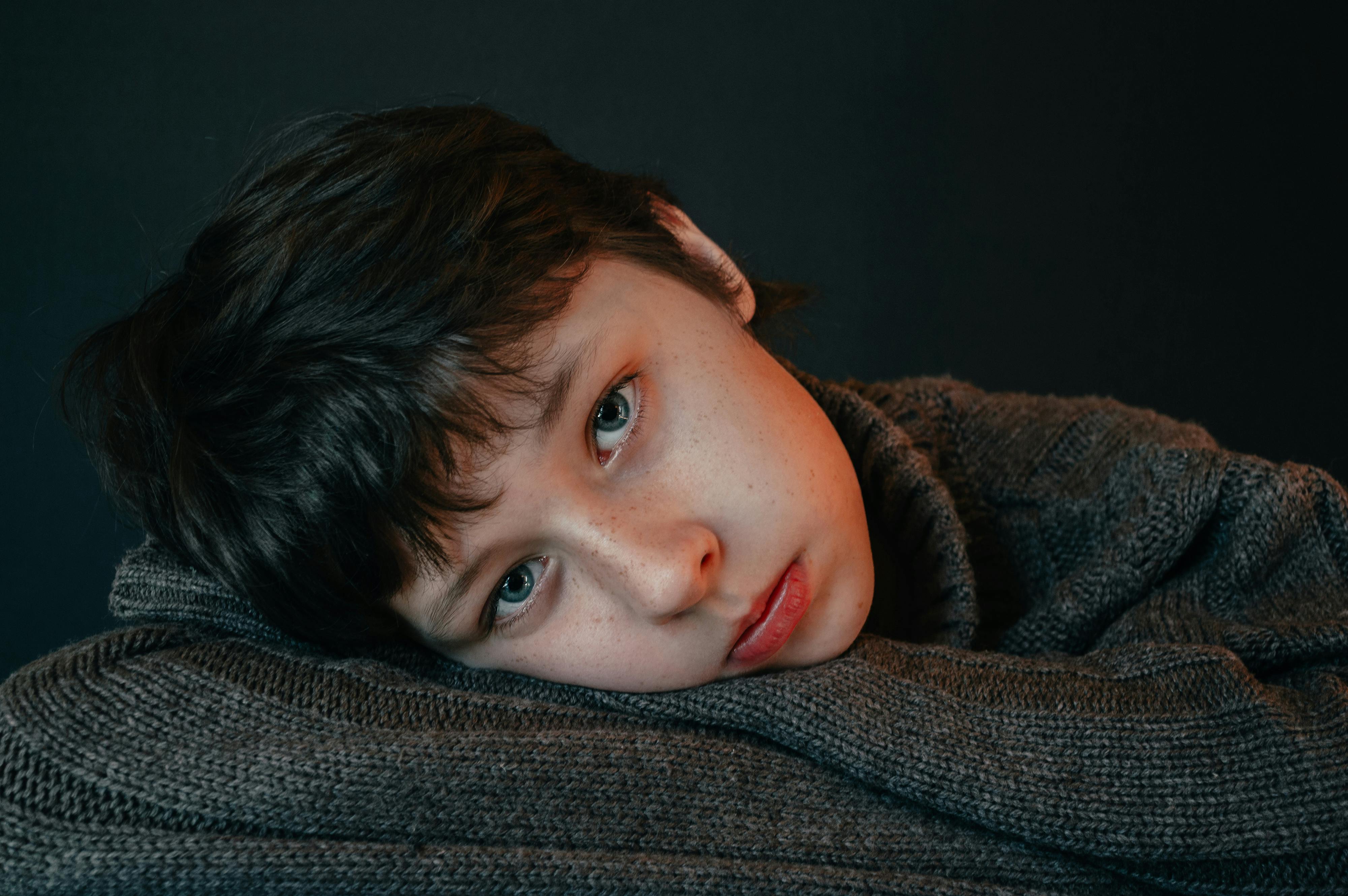 boy with head leaning on gray knitwear