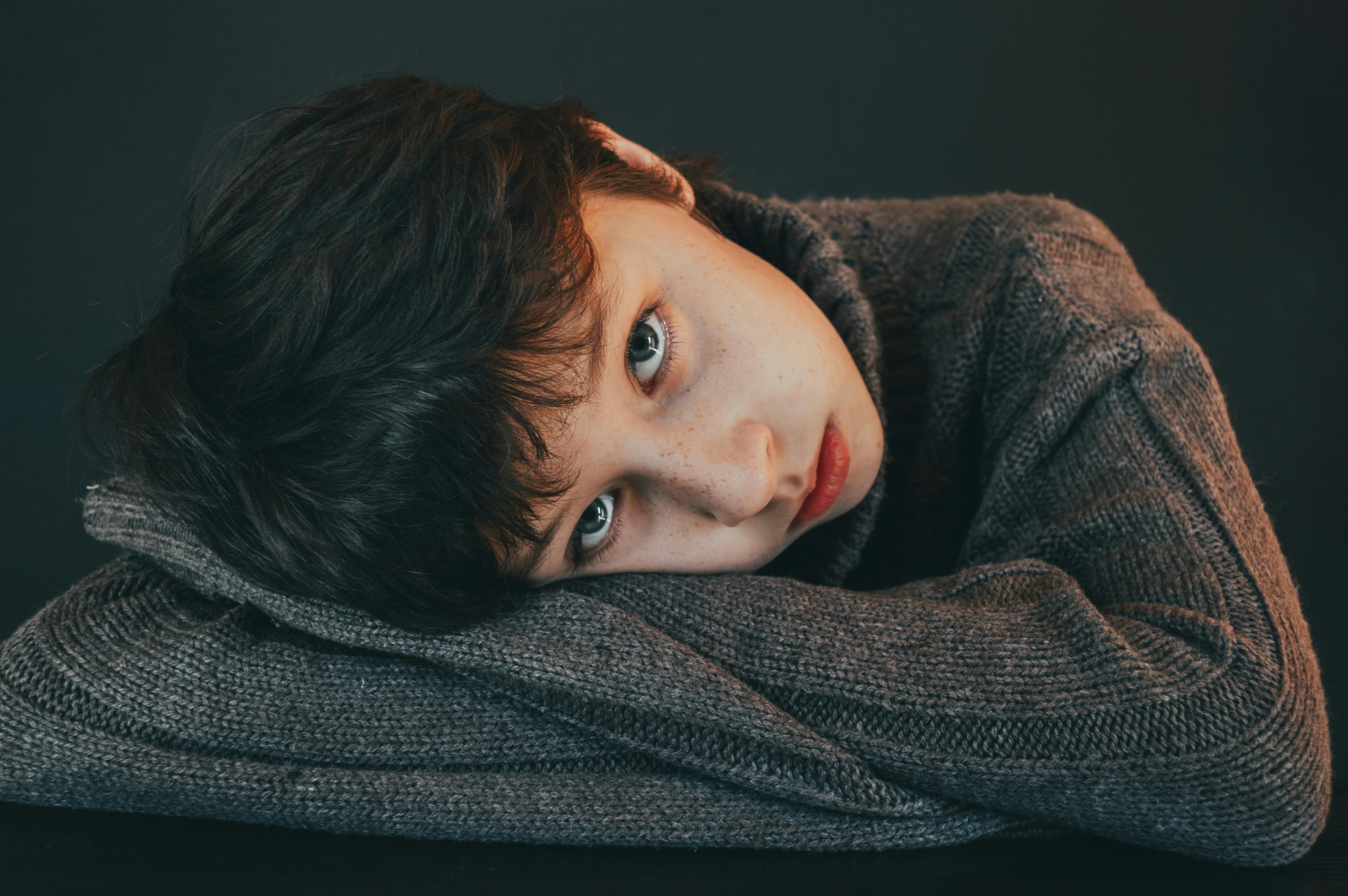 boy with head leaning on gray knitwear