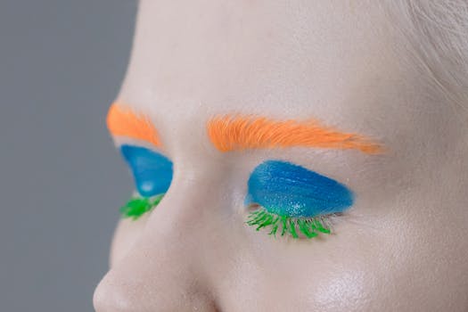 Close-up of a vibrant makeup look featuring orange eyebrows and blue eyeshadow.