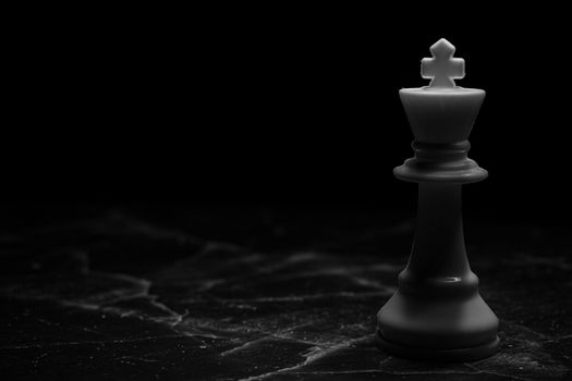 Striking image of a white chess king on a dark marble surface, symbolizing strategy and power.