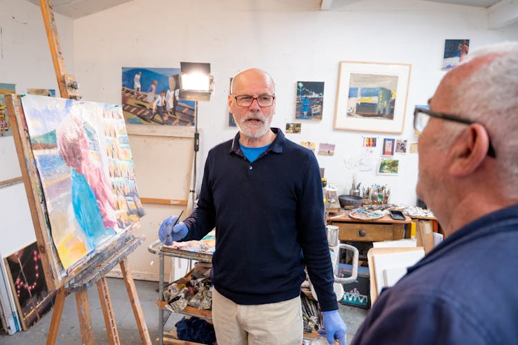 Man With Blue Hand Gloves Standing Near Painting On Steel Easel