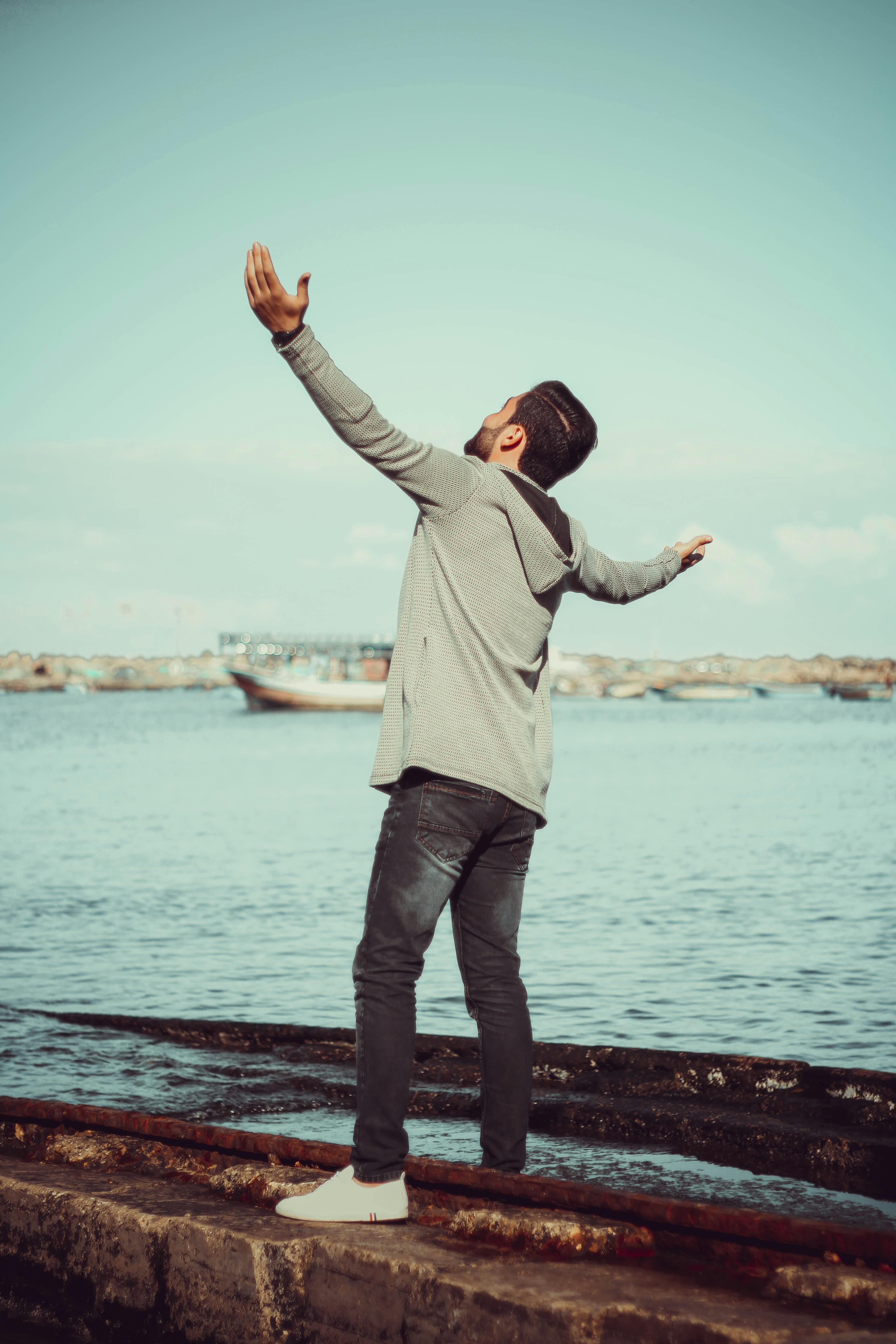 一个男人站在海边，快乐地拥抱户外的自由和休闲