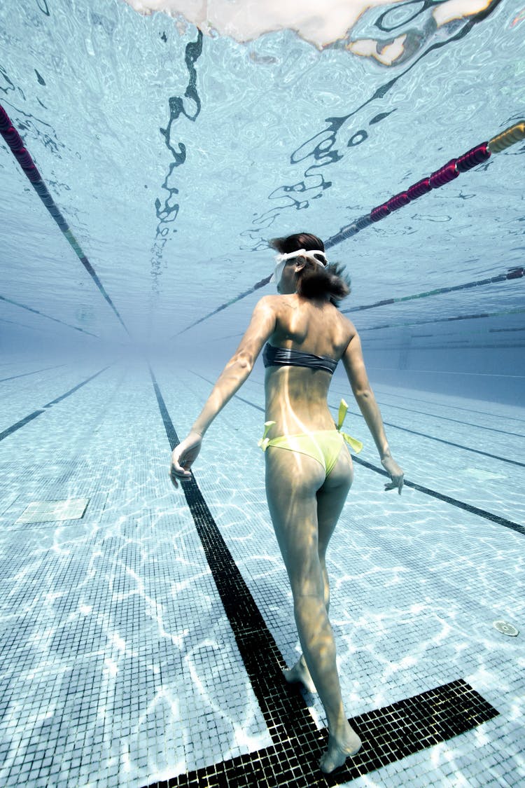 Unrecognizable Woman Swimming Underwater In Pool