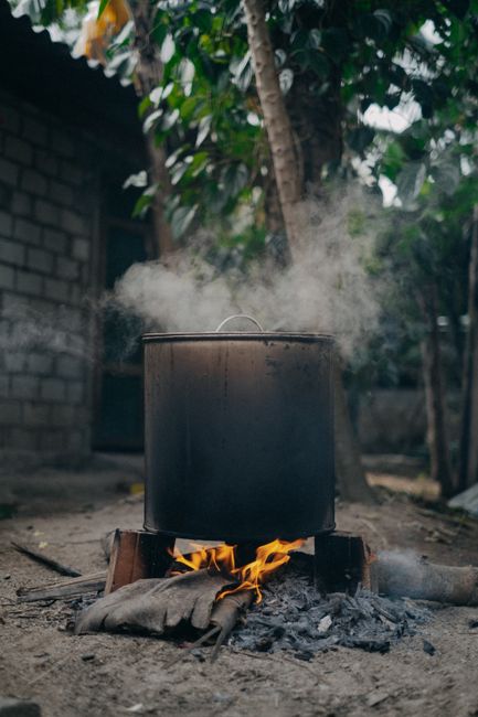 Large pot steaming over firewood outdoors in Vietnam, showcasing rustic cooking tradition.