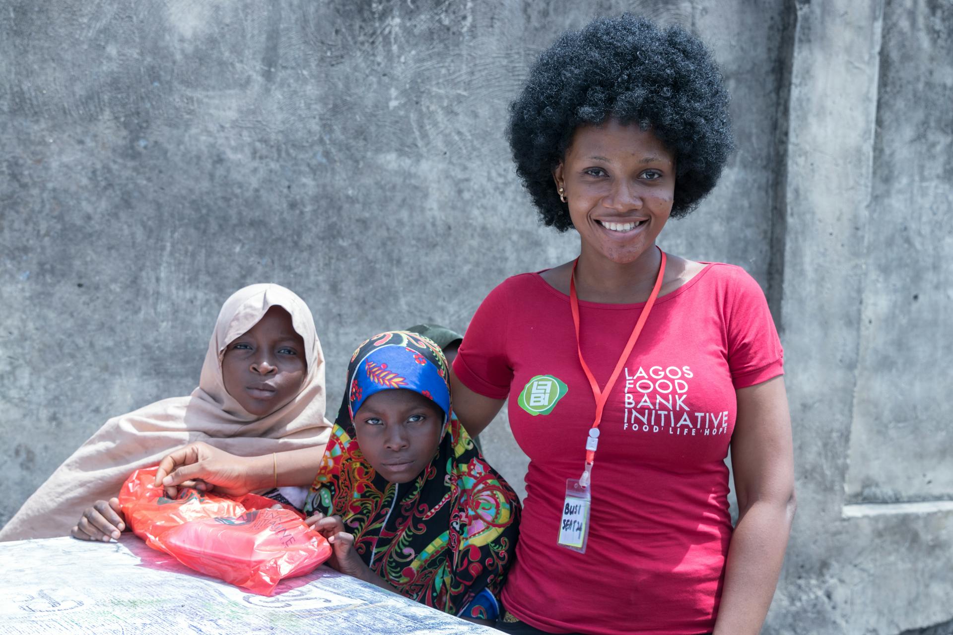 Volunteers and beneficiaries smiling at Lagos Food Bank Initiative, showcasing community support.