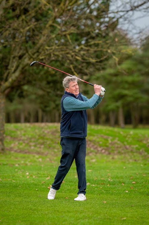 Elderly Man in Blue Jacket and Black Pants Playing Golf