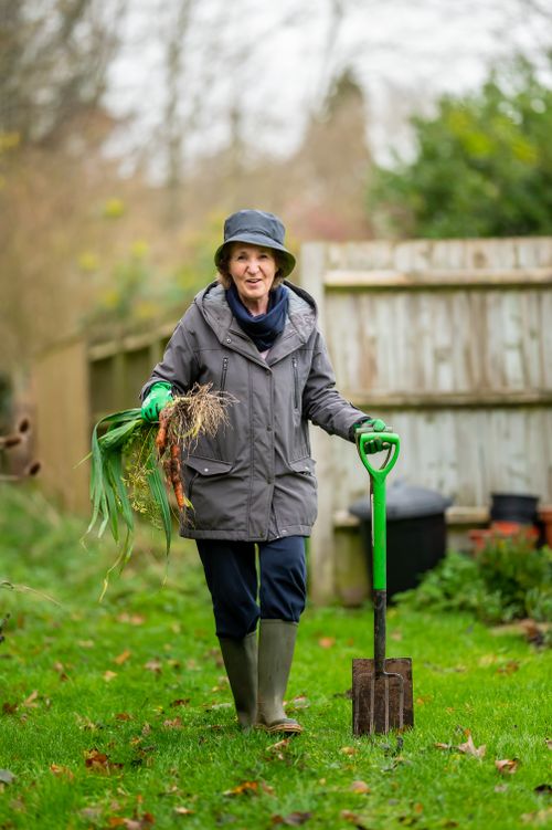 Free Elderly woman in a garden with a shovel and fresh harvest on a fall day. Stock Photo