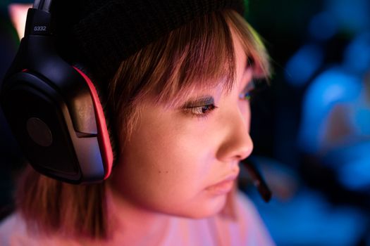 Profile view of a focused gamer wearing a headset intensely playing a game.