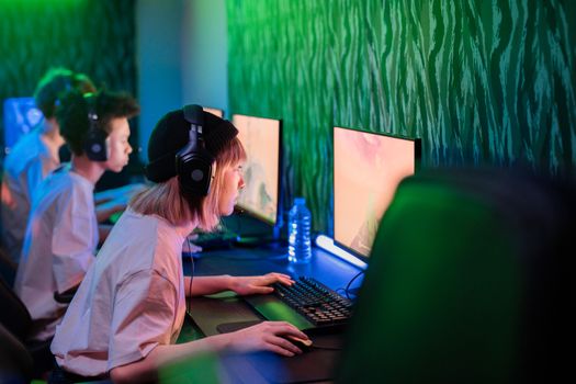 Gamers intensely focused on playing in a vibrant cybercafe environment.