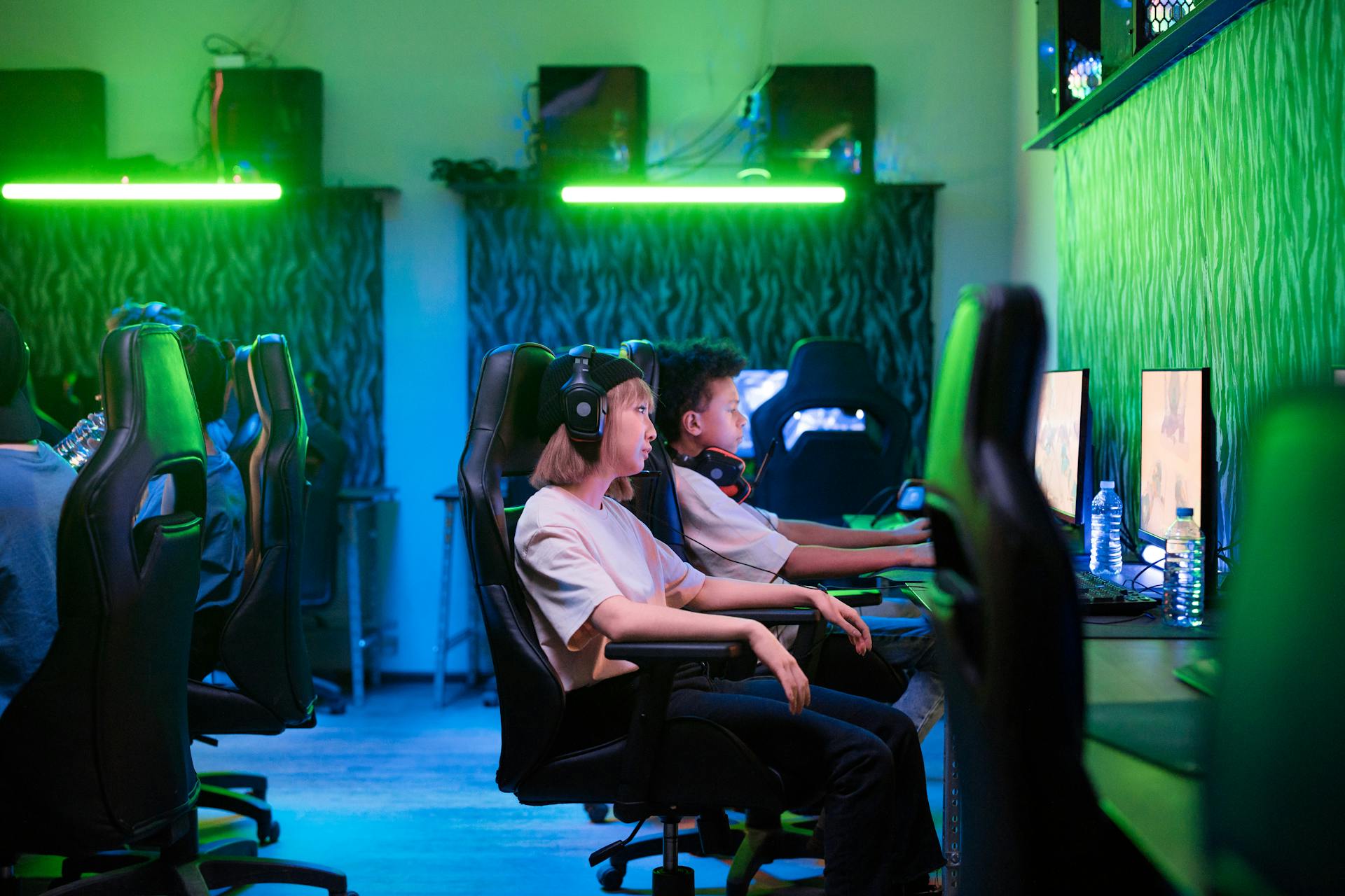 Teenagers immersed in online gaming in a neon-lit room, showcasing modern technology.