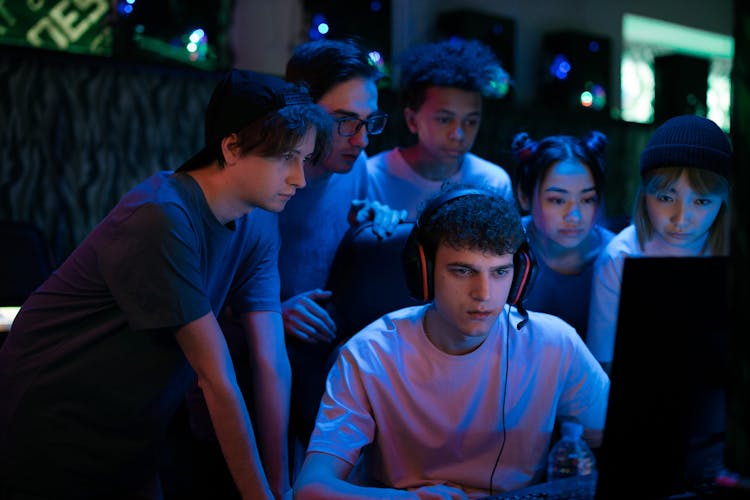 Group Of Teenagers Watching A Man Play Game On Computer