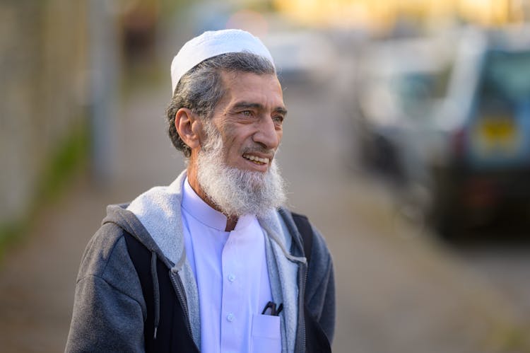 A Bearded Man Wearing A White Kufi Hat