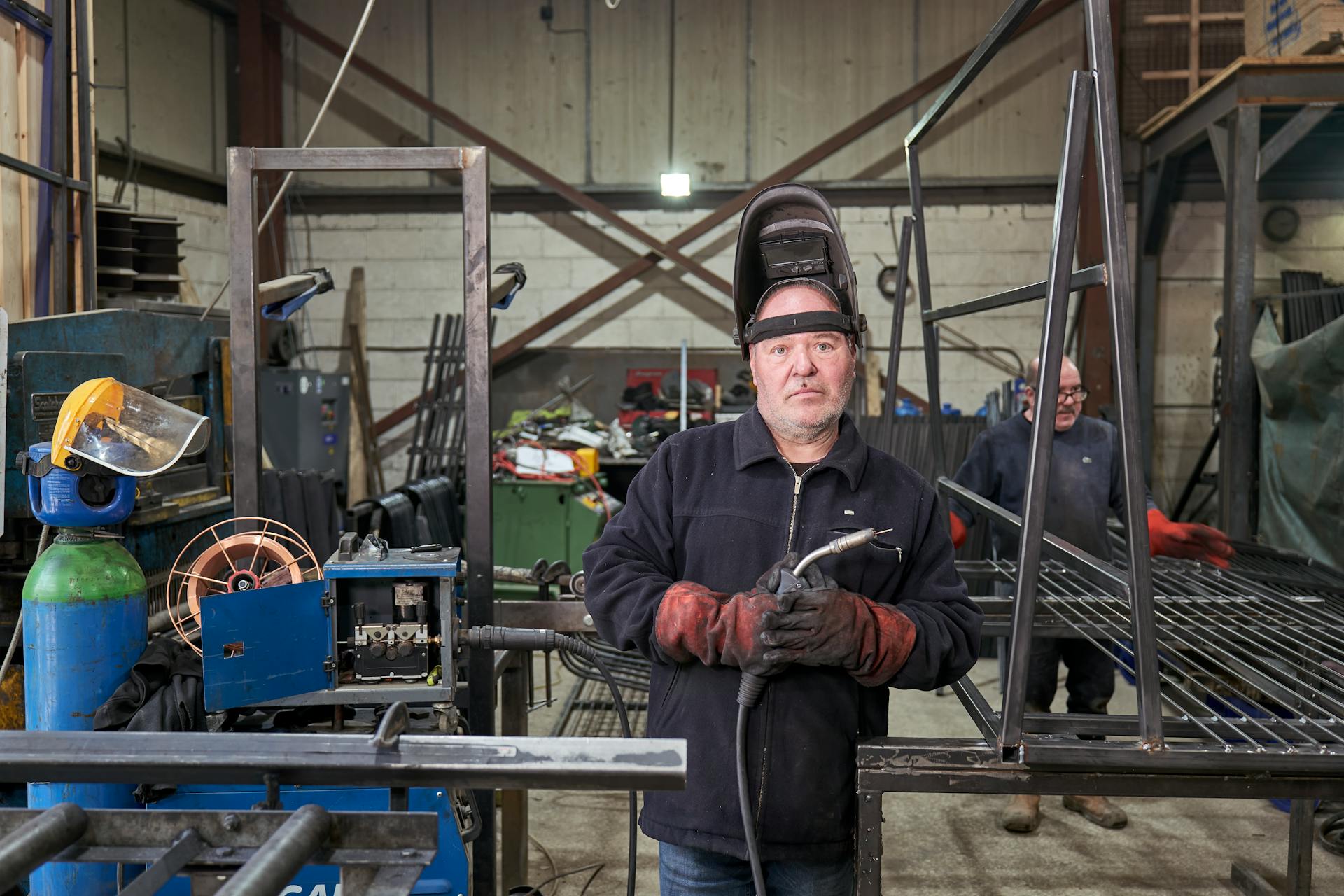 Skilled welders working with metal and equipment in an industrial workshop setting.