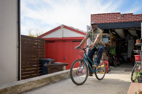 Free Man in Green Button Up Shirt and Blue Denim Jeans Riding a Blue Bicycle Stock Photo