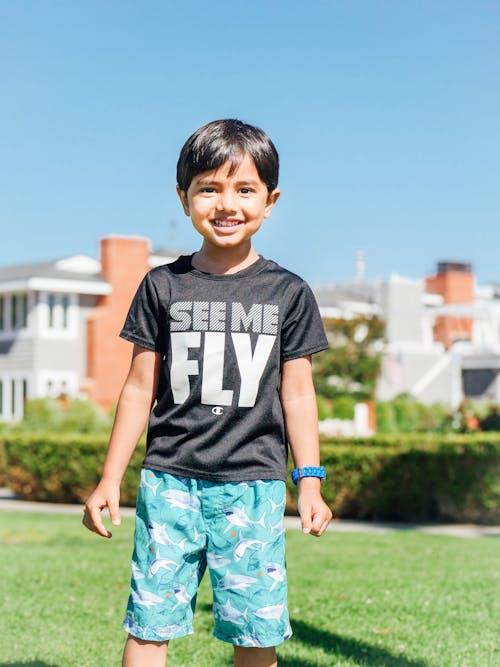 Boy in Black Crew Neck T-shirt Standing on Green Grass Field