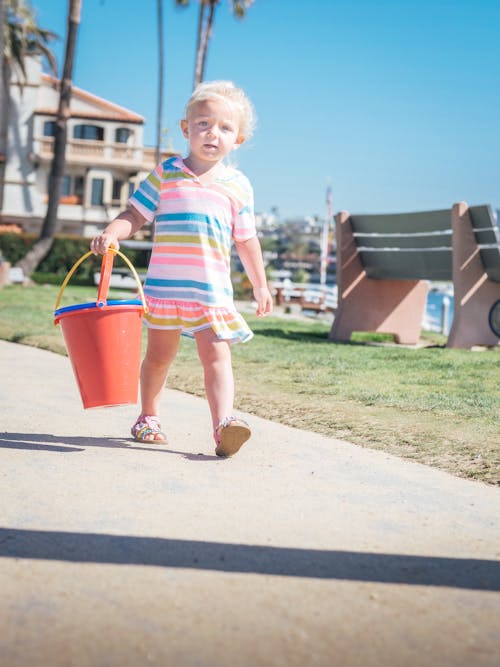 Girl in Stripe Dress Holding Red Plastic Bucket