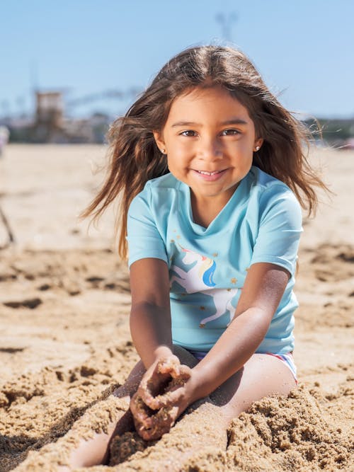 Girl in Blue Crew Neck T-shirt Sitting on Brown Sand