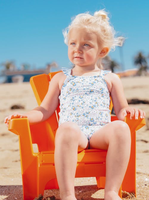 Charming girl in swimsuit in armchair on beach