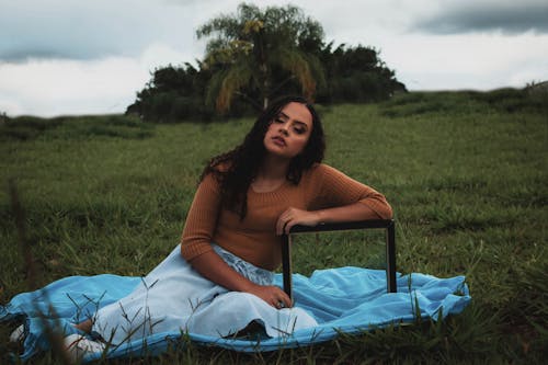 Woman Sitting on Blanket in Front of Tropical Trees 