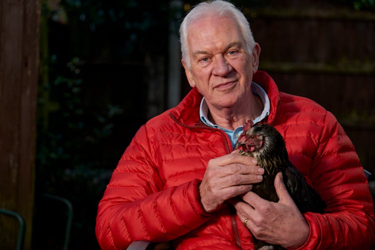 An Elderly Man Holding A Chicken