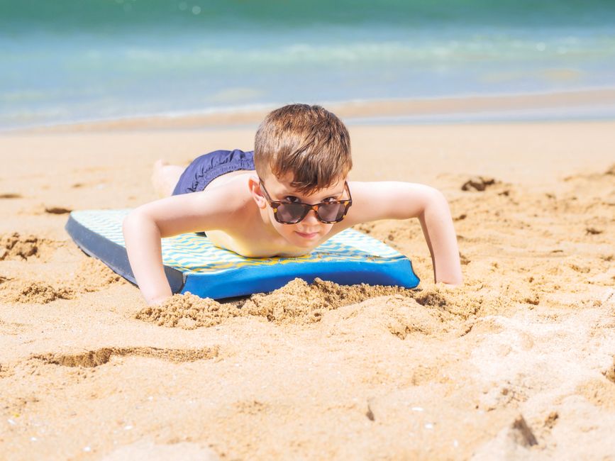 Young boy on a boogie board enjoying a sunny day at the beach. Fun and leisure under the sun.