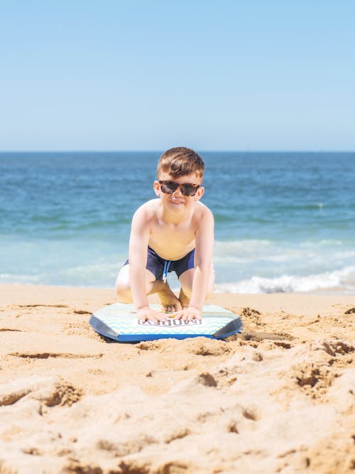 Free Man in Black Sunglasses Sitting on White Surfboard on Beach Stock Photo