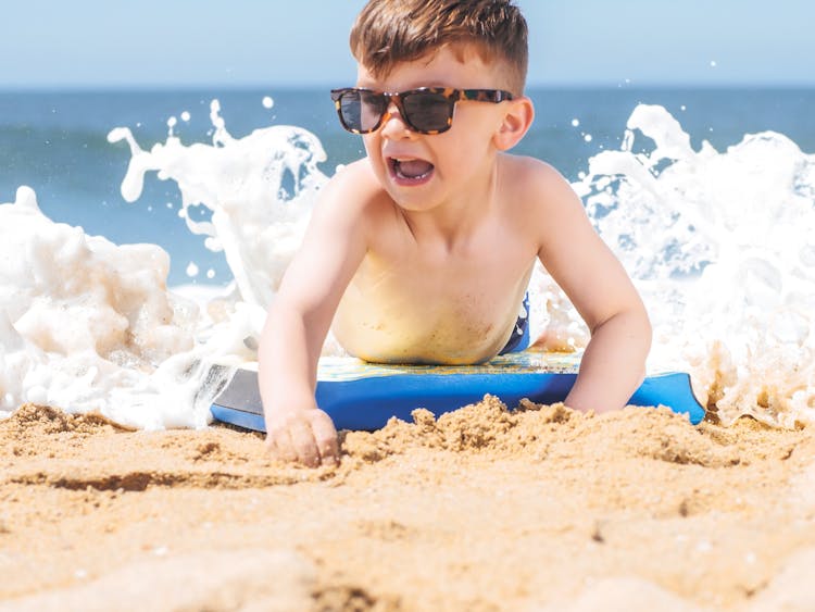 A Boy Wearing Sunglasses Soaking On The Beach