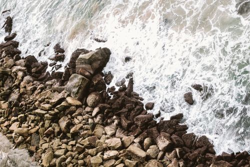 Free A stunning aerial view of a rocky seashore with waves crashing against the rocks. Stock Photo