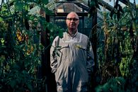 Man in Gray Zip Up Jacket Standing Near Green Plants