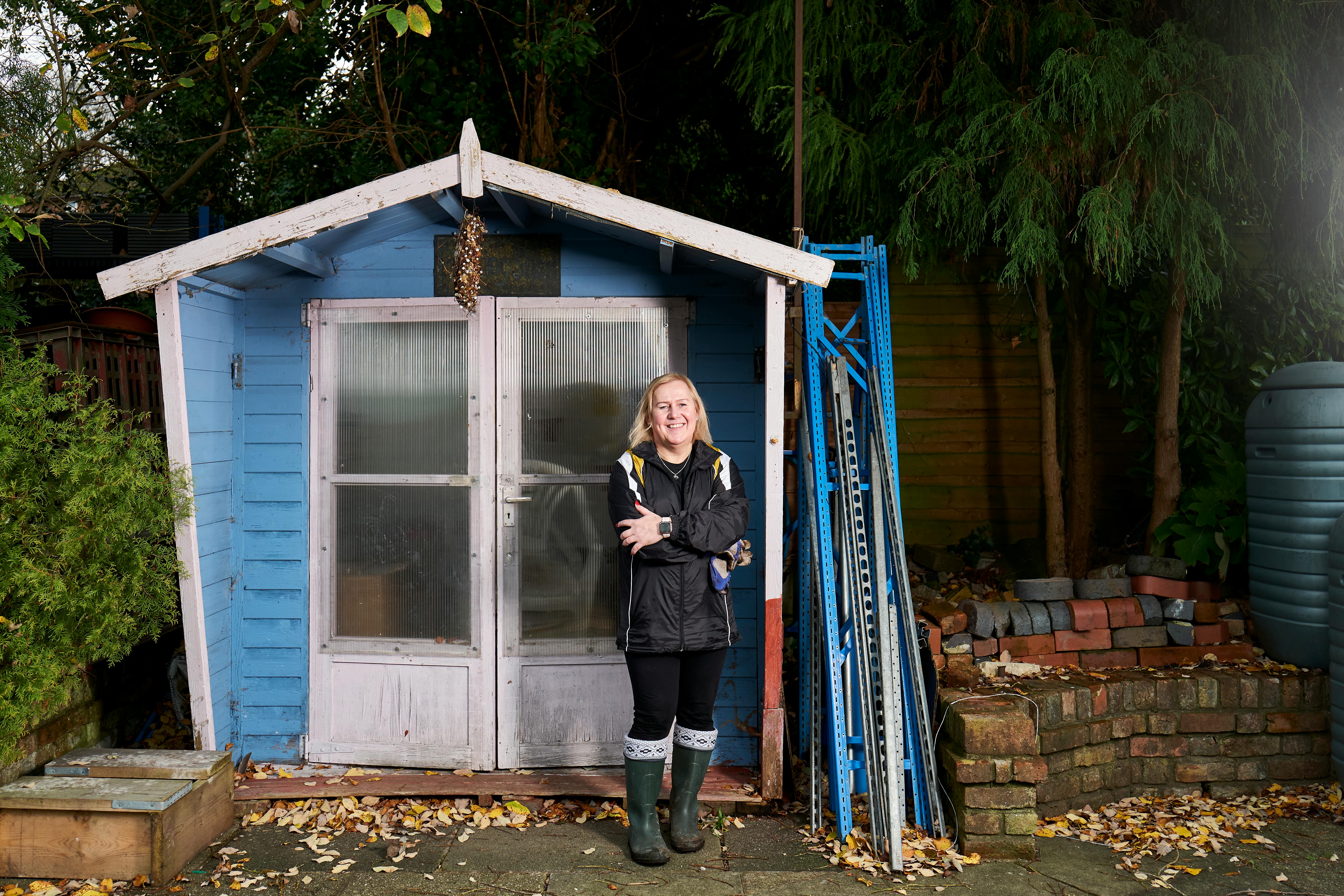 A Woman in Blue Jacket Standing In Front of a Blue Shed