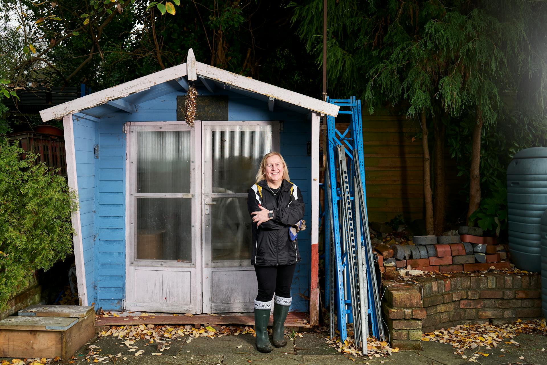 A Woman in Blue Jacket Standing In Front of a Blue Shed