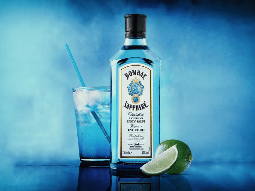 Stylish blue drink featuring Bombay Sapphire gin, lime, and ice against a vibrant background.