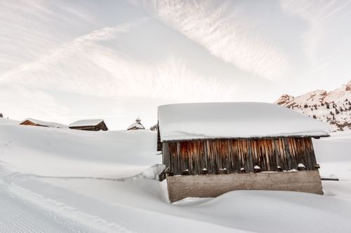 Free Scenic view of a rustic snowy village at sunrise with wooden cabins and mountain backdrop. Stock Photo