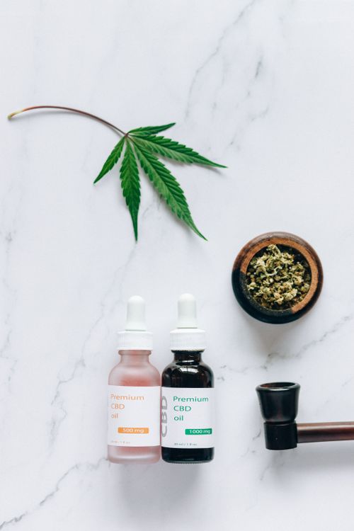 Free Flat lay of CBD oil bottles and hemp leaf, emphasizing natural wellness products. Stock Photo