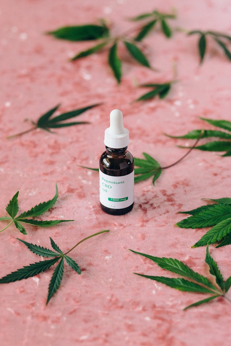 A Serum Bottle Surrounded By Cannabis Leaves