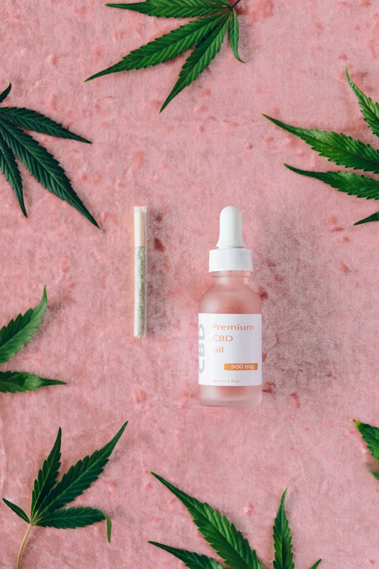 A CBD Oil Bottle Beside A Joint