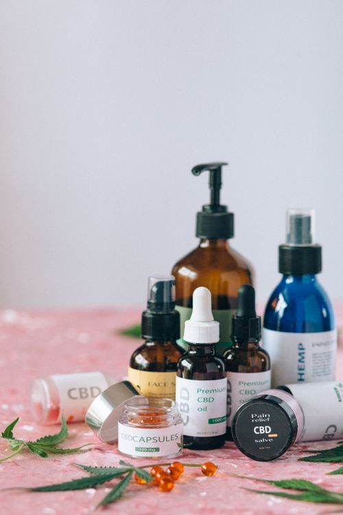Free A variety of CBD and hemp products displayed on a pink surface with scattered leaves. Stock Photo