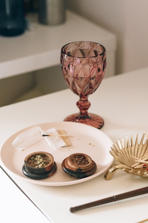 A Cannabis Grinder beside a Glass of Water