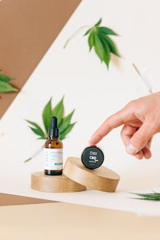 Minimalist shot of CBD oil and cream on wooden platforms with cannabis leaves for wellness.